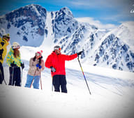 Turistas esquiando e pousando para foto em frente a uma montanha coberta por neve